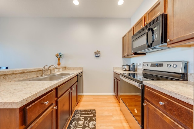 kitchen with appliances with stainless steel finishes, light hardwood / wood-style flooring, and sink