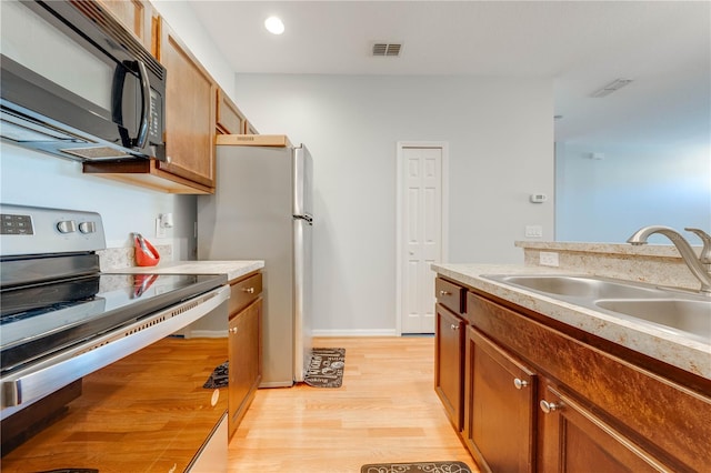 kitchen featuring sink, light wood-type flooring, and appliances with stainless steel finishes