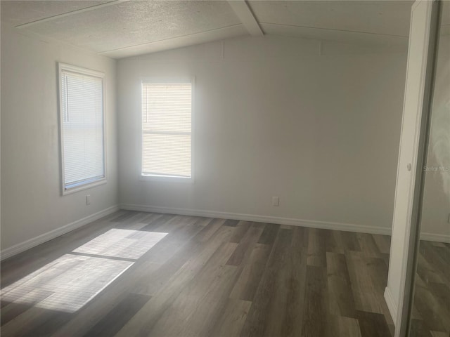 spare room with vaulted ceiling with beams and dark wood-type flooring