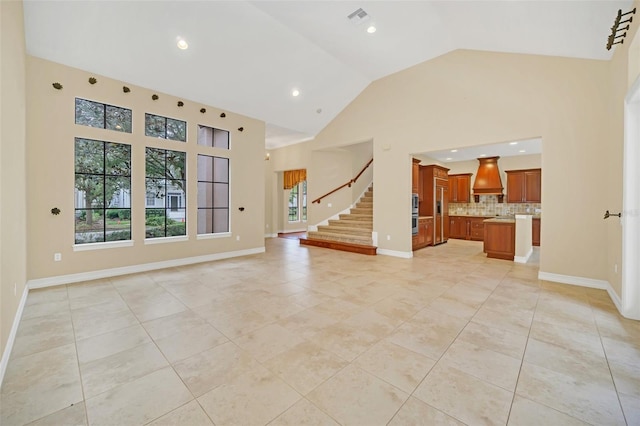 unfurnished living room with light tile patterned floors and high vaulted ceiling