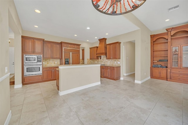 kitchen with a center island, built in appliances, premium range hood, and backsplash