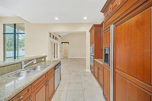 1233 Aquila Loop, Celebration, FL 34747 - kitchen featuring a sink, built in appliances, light stone counters, light tile patterned floors, and brown cabinets