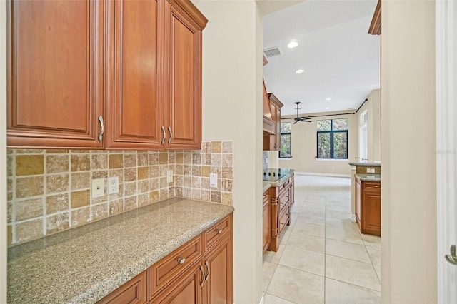 kitchen featuring tasteful backsplash, light stone counters, ceiling fan, and light tile patterned flooring