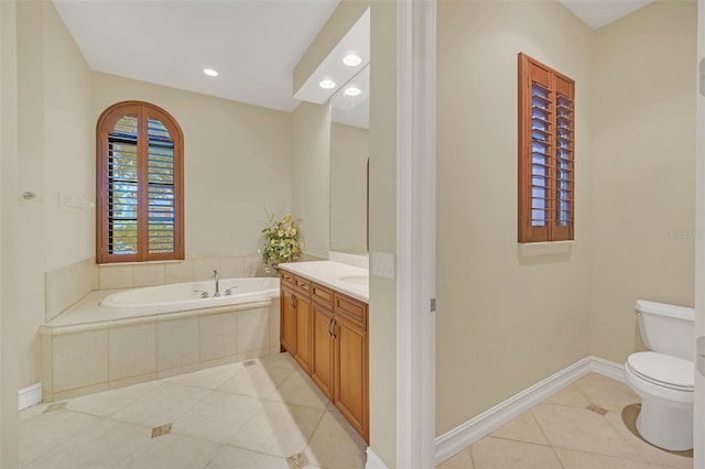 bathroom featuring tile patterned floors, tiled tub, vanity, and toilet