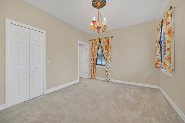 carpeted empty room with a notable chandelier