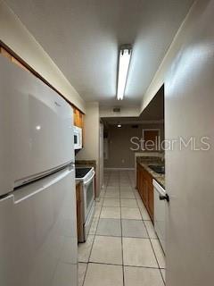 kitchen featuring light tile patterned flooring and white appliances