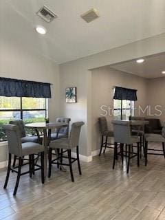 dining room with light wood-type flooring and vaulted ceiling