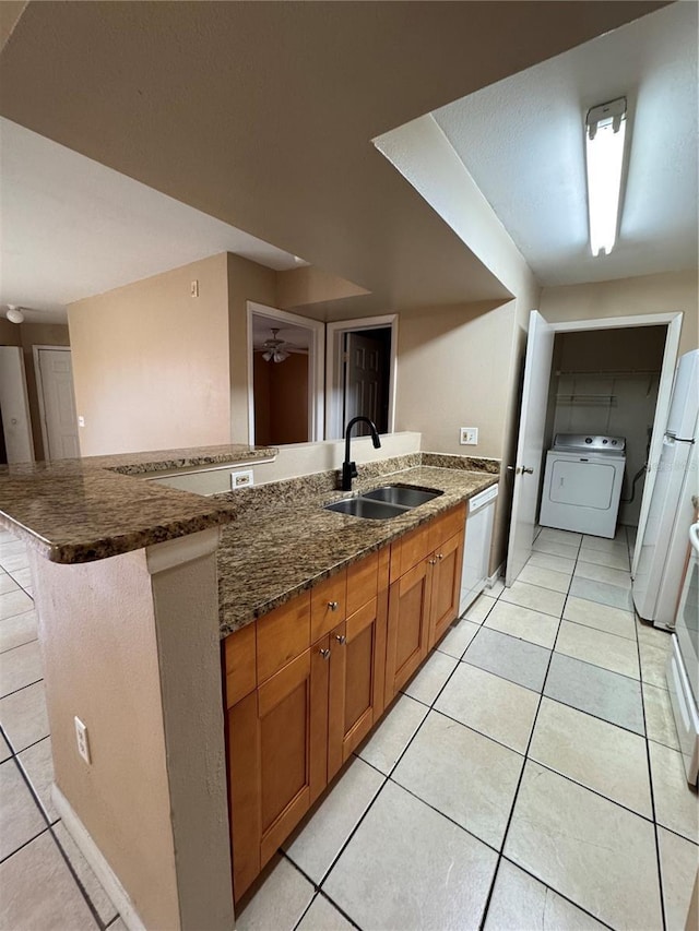 kitchen featuring sink, dishwasher, a kitchen bar, washer / clothes dryer, and kitchen peninsula