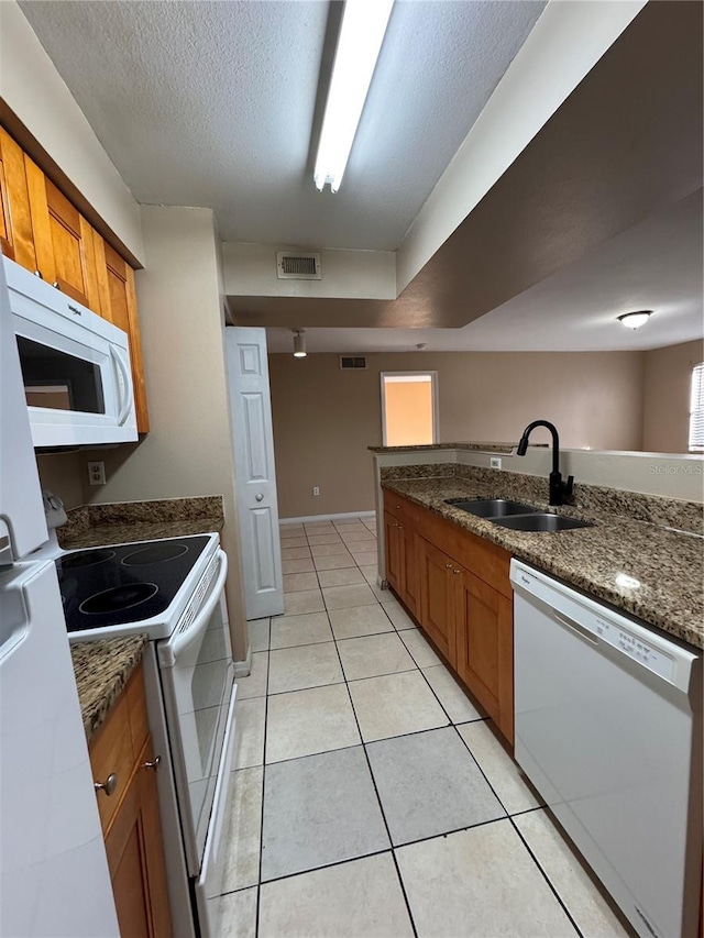 kitchen featuring sink, white appliances, dark stone countertops, a textured ceiling, and light tile patterned flooring