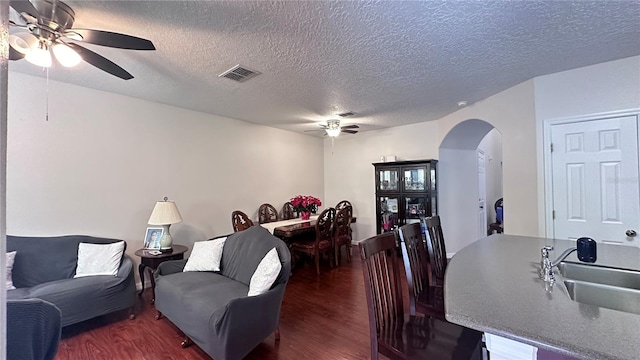 living room with a textured ceiling, ceiling fan, sink, and dark hardwood / wood-style floors