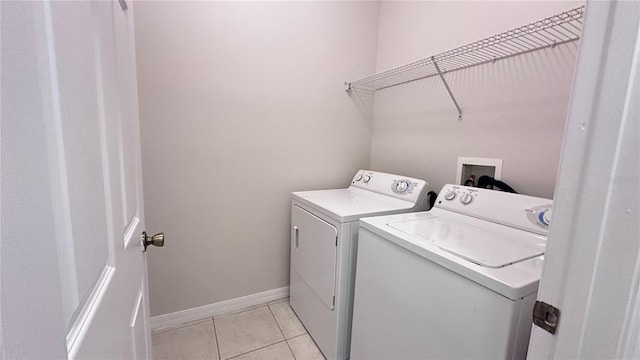 clothes washing area featuring washer and clothes dryer and light tile patterned floors