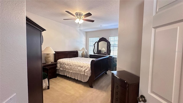 bedroom with ceiling fan, light colored carpet, and a textured ceiling