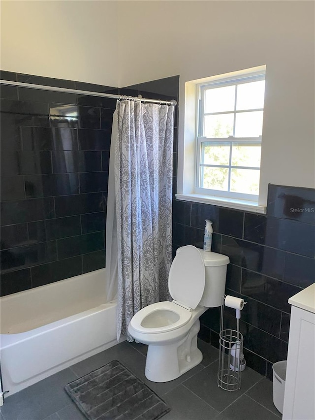 full bathroom featuring tile patterned floors, shower / bath combo with shower curtain, tile walls, and vanity