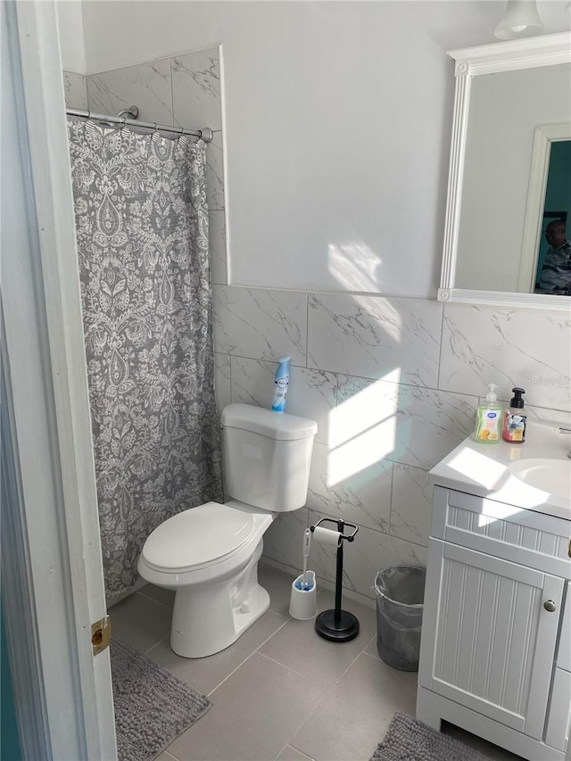 bathroom featuring toilet, a shower with curtain, tile walls, tile patterned floors, and vanity