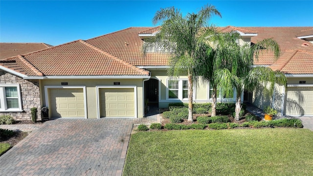 mediterranean / spanish-style home featuring a front lawn and a garage