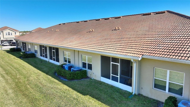 rear view of house with central AC unit and a lawn