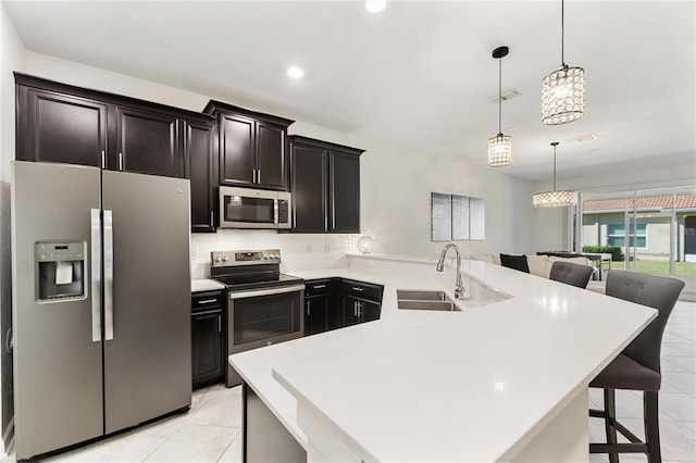 kitchen featuring a breakfast bar, sink, hanging light fixtures, and appliances with stainless steel finishes