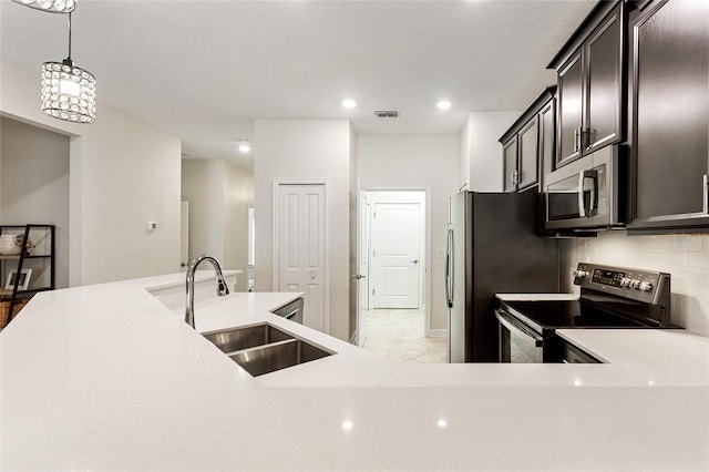 kitchen featuring sink, pendant lighting, a textured ceiling, decorative backsplash, and appliances with stainless steel finishes