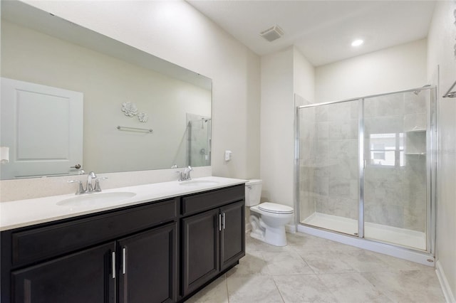 bathroom with tile patterned floors, a shower with door, vanity, and toilet