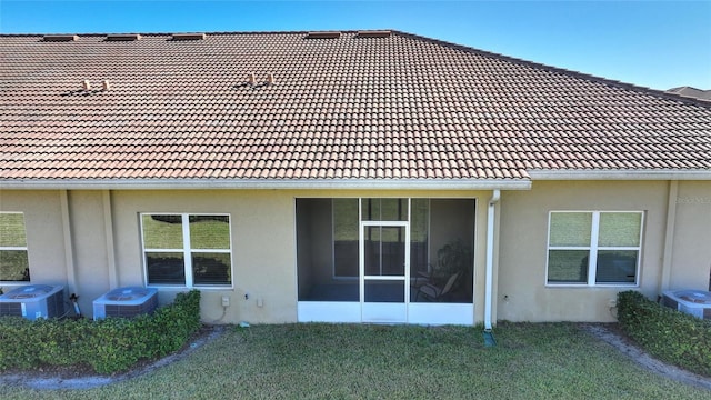 rear view of property featuring a lawn and central AC