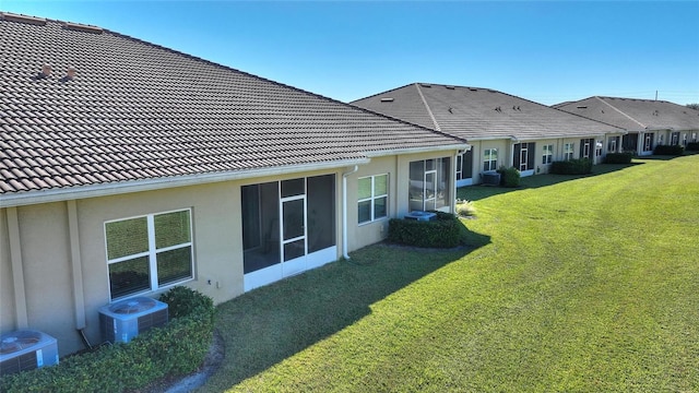 rear view of property with a lawn and cooling unit