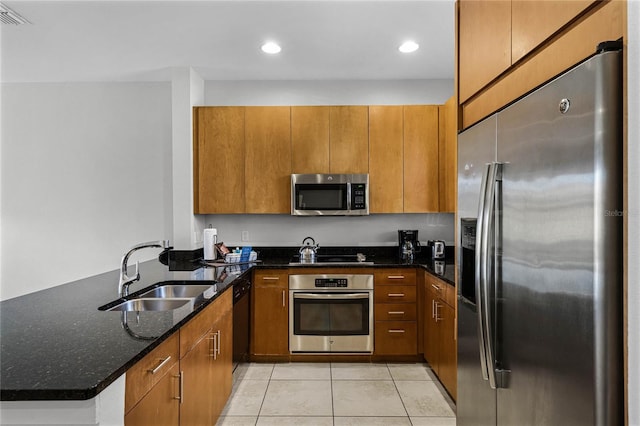 kitchen featuring sink, dark stone countertops, light tile patterned floors, kitchen peninsula, and stainless steel appliances