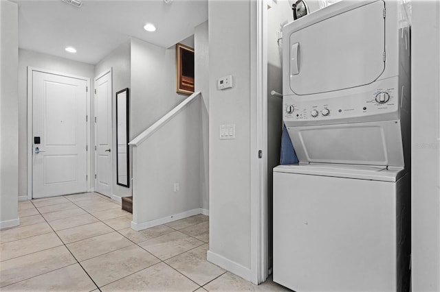 laundry area featuring light tile patterned floors and stacked washer / dryer