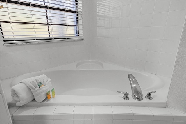 bathroom featuring a relaxing tiled tub and plenty of natural light