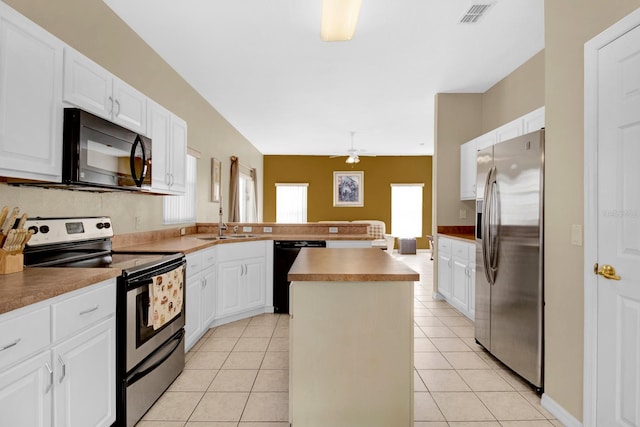 kitchen with a center island, black appliances, ceiling fan, light tile patterned floors, and white cabinetry