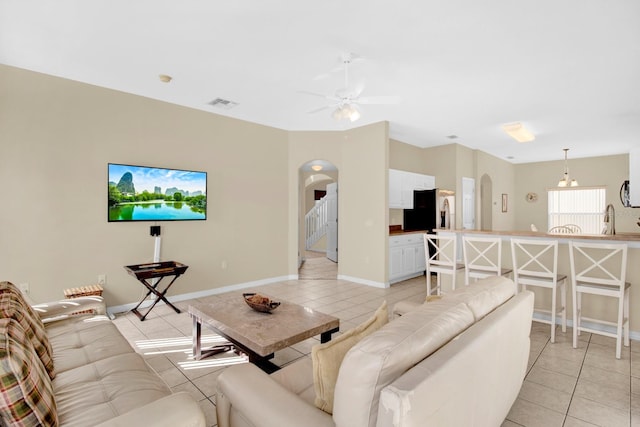 tiled living room featuring ceiling fan and sink