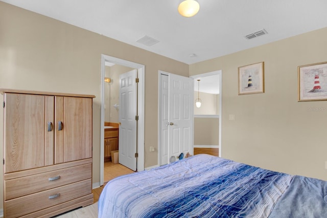 bedroom with connected bathroom and light wood-type flooring