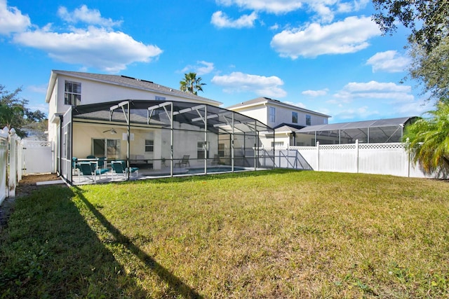 rear view of property with a yard, a patio area, and a lanai