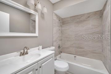 full bathroom with toilet, vanity, and tiled shower / bath combo