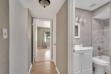 full bathroom featuring vanity, hardwood / wood-style flooring, toilet, and tiled shower / bath