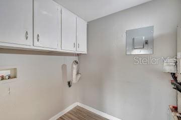 clothes washing area featuring cabinets, hookup for a washing machine, electric panel, and hardwood / wood-style flooring