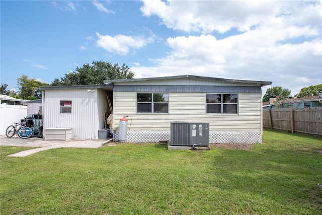 back of property featuring a lawn and central air condition unit