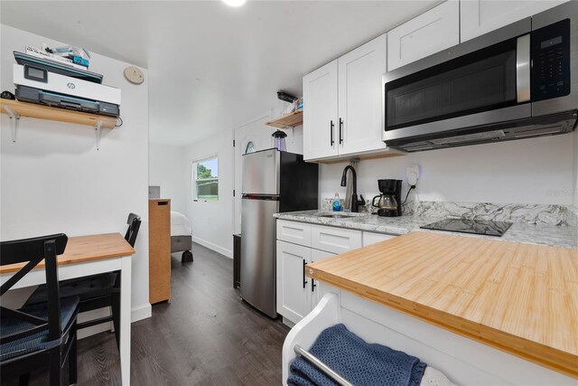 kitchen featuring light stone countertops, white cabinetry, sink, stainless steel appliances, and dark hardwood / wood-style floors