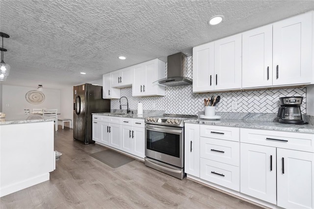 kitchen with stainless steel electric stove, white cabinets, wall chimney exhaust hood, light wood-type flooring, and decorative light fixtures