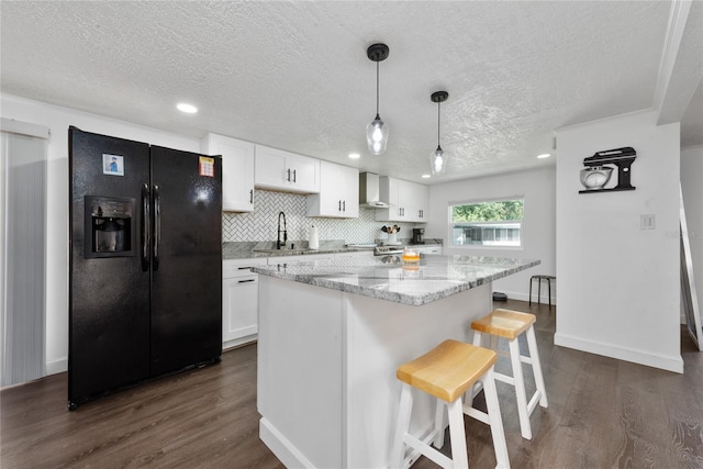 kitchen featuring black fridge with ice dispenser, a textured ceiling, wall chimney range hood, white cabinets, and dark hardwood / wood-style floors