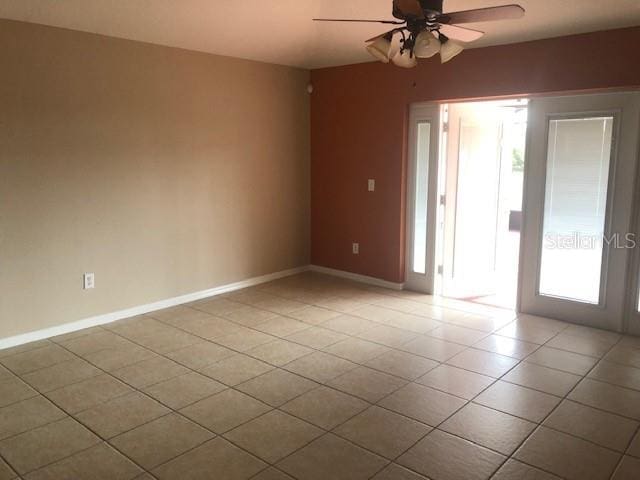 empty room featuring light tile patterned floors, ceiling fan, and a healthy amount of sunlight