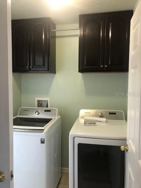 washroom with washing machine and clothes dryer and cabinets