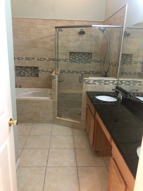 bathroom featuring shower with separate bathtub, vanity, and tile patterned floors