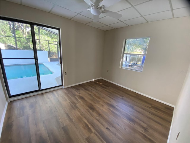 empty room with a paneled ceiling, ceiling fan, and dark wood-type flooring