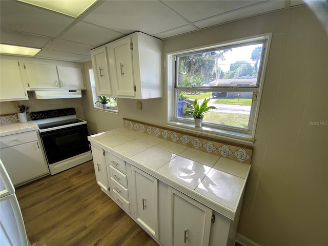 kitchen featuring dark hardwood / wood-style flooring, a drop ceiling, white electric stove, white cabinetry, and tile counters