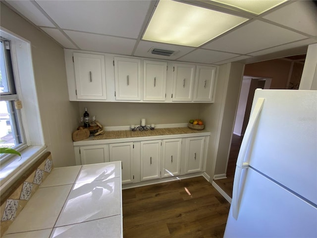 kitchen featuring white cabinets, white refrigerator, dark hardwood / wood-style floors, and a paneled ceiling