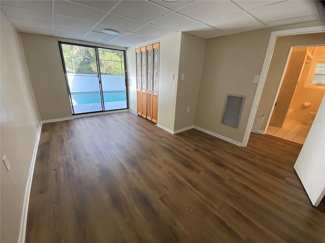 empty room featuring dark hardwood / wood-style floors and a drop ceiling