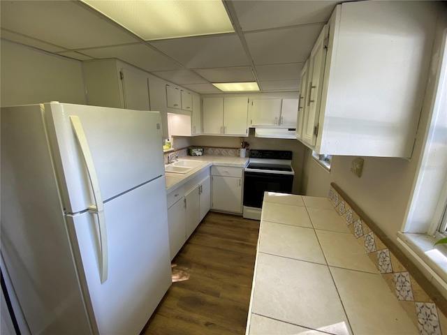 kitchen with sink, a drop ceiling, dark wood-type flooring, white appliances, and white cabinets