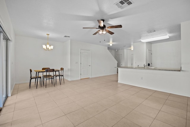 living room featuring ceiling fan with notable chandelier, light tile patterned floors, and a textured ceiling