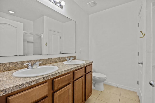 bathroom with toilet, vanity, tile patterned floors, and an enclosed shower