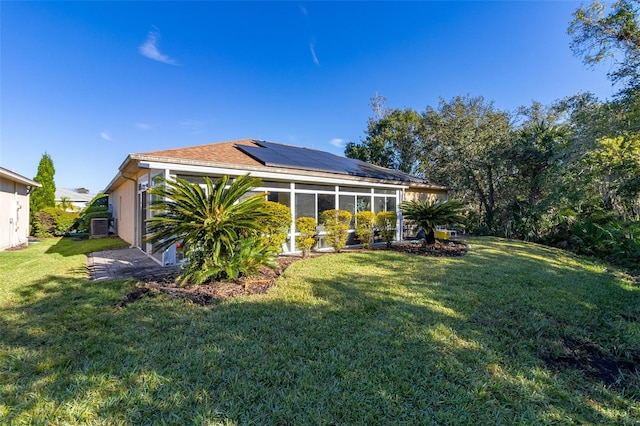 rear view of house with a sunroom, solar panels, and a yard